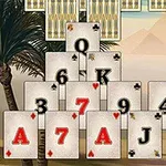 피라미드 형태로 배열된 카드들 앞에 사막 배경과 야자수가 있는 모습