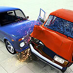 두 대의 차량, 파란색과 빨간색,이 충돌하여 파편과 불꽃이 튀는 모습