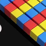 검정 배경 위에 흰색 공이 컬러풀한 빨강, 노랑, 파랑 블록들 쪽으로 굴러가는 모습