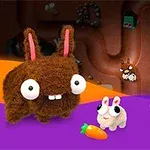 털이 많은 큰 귀를 가진 토끼와 두 마리의 작은 흰색 토끼가 함께 있으며, 주변에 당근이 놓여 있다