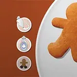 진저브레드 남자 모양의 쿠키가 접시 위에 놓여 있고, 왼쪽에는 아이싱 가방과 파란색 병, 쿠키 아이콘이 나열되어 있습니다