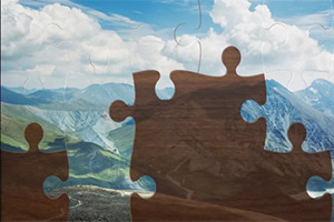 산의 전경을 배경으로 불완전하게 맞춰진 나무 퍼즐 조각들이 있는 이미지