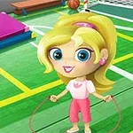 귀여운 금발 소녀가 초록색 체육관 바닥에서 줄넘기를 하고 있다