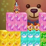 분홍색, 노란색, 파란색, 녹색 블록들이 쌓여 있고, 뒤에 큰 곰 인형과 작은 곰 인형 두 개가 모자 쓰고 있으며, 중간에는 두 명의 광대가 있다