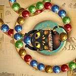 고대 이집트 벽화를 배경으로 한 색색의 구슬들이 뱀 모양으로 배열되어 있으며 중앙에 입을 벌린 검은 고양이 조각상이 있습니다